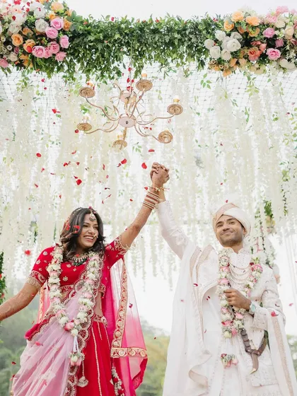 A moment of pure triumph and joy. Sanket and Sakshi celebrate their union under a shower of petals, their hands raised in a beautiful, celebratory pose.