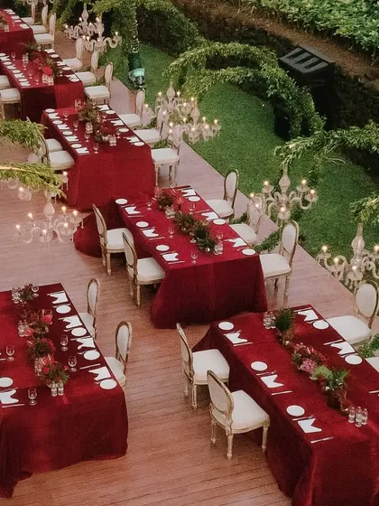 Another perspective of the stunning red-themed dinner setup, highlighting the contrast between the rich red tables and the natural green surroundings.