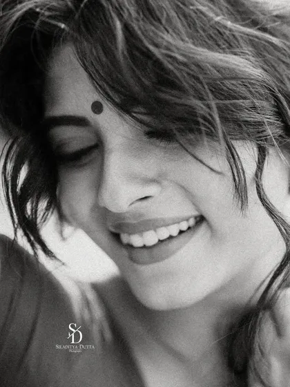 A joyful black and white close-up. The model's bright, uninhibited smile is captured with a soft, grainy texture that adds a timeless and authentic feel.