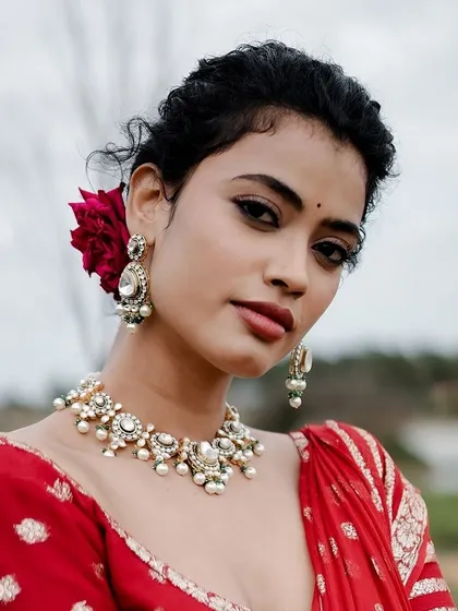Embracing the timeless elegance of a red saree. This look, on a model with beautiful curly hair, is all about tradition and grace.