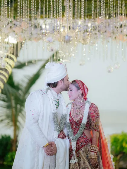 A tender forehead kiss under a canopy of hanging crystals and florals. These are the quiet, intimate moments that I design spaces for.