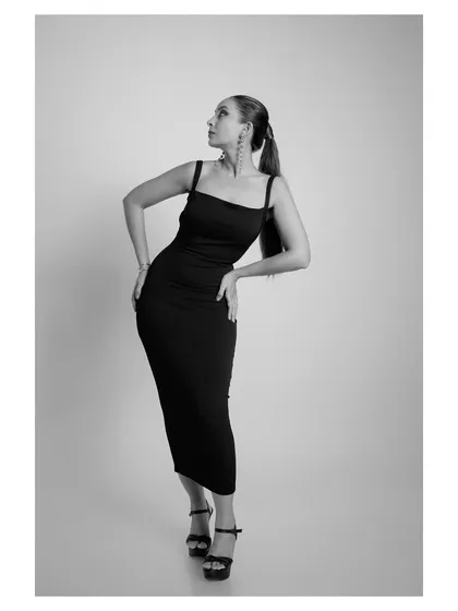 A full-body, black and white studio shot of a model in a sleek black dress. The monochrome treatment adds a touch of drama and timeless sophistication.