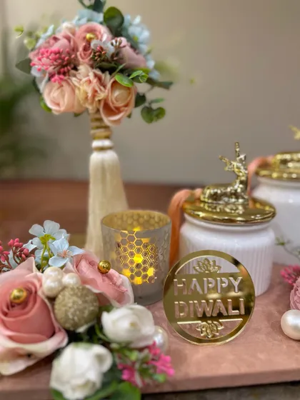 A close up of our pink marble tray hamper, highlighting the 'Happy Diwali' tag, the honeycomb pattern on the candle holder, and the beautiful floral bouquet. Every detail is thoughtfully curated.