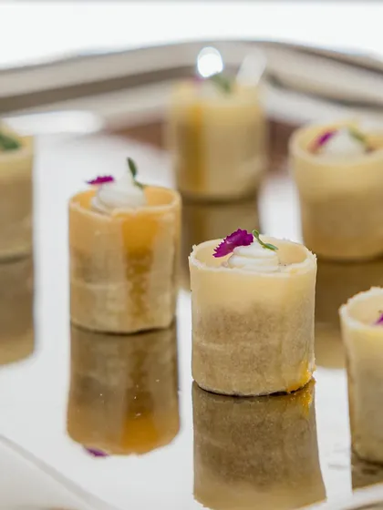 Delicate canapés served on a mirrored tray for the Valentino event. The presentation is clean and minimalist, letting the simple forms and flavors speak for themselves.