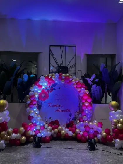 A circular ring backdrop is a popular and versatile choice for many events like engagements or anniversaries. Here, I have decorated it with a dense garland of pink, white, and gold balloons and soft lighting to highlight the couple's names.