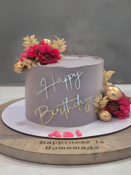 A sophisticated grey cake with pops of magenta from the floral decorations and gold accents, creating a modern and stylish look.