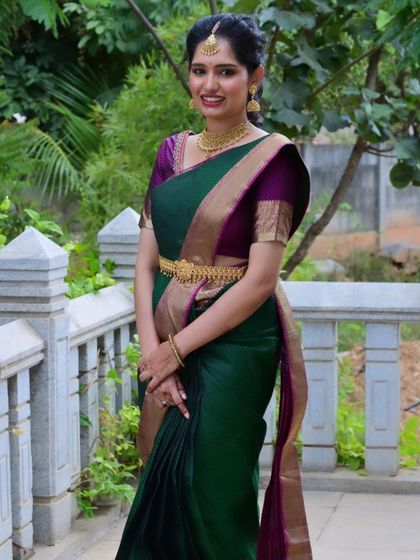 A full-length view of this elegant engagement look. The green and purple silk saree is beautifully styled, and the makeup is designed to look fresh and radiant both in person and in photos.
