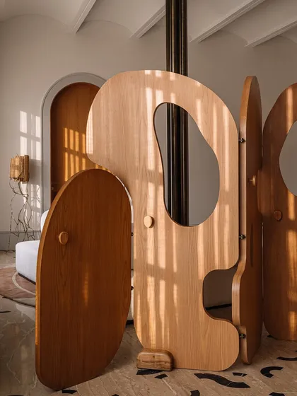 Our 'Hide N Seek' screen is furniture that invites play. Designed to divide a large suite into a salon and bedroom, its amoebic wooden panels have organic cutouts that frame views and create intriguing vignettes. It’s a sculptural piece that is both a space divider and an interactive art form.