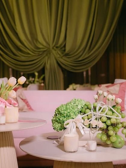 A close-up of the pink lounge sofa, showing the unique centerpiece made of green grapes and hydrangeas, reflecting the playful and chic theme of the "Big Bow Affair."