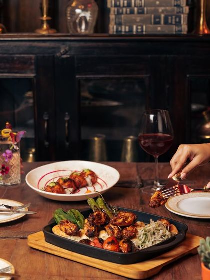 A table set for a royal feast. Our grilled platters and appetizers are meant to be shared and savored, creating a conversation not just around the food, but with the food itself.