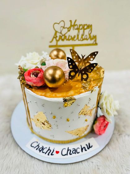A beautiful anniversary cake for "Chachi & Chachu," showing that every family celebration deserves a special touch. The cake features gold leaf, flowers, and butterfly accents.