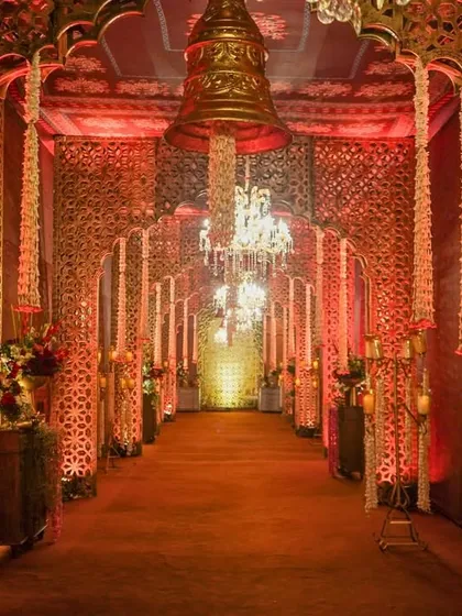 A dramatic entrance walkway framed by golden jali panels and lit by a series of magnificent crystal chandeliers, creating a path of pure opulence.