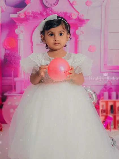 Holding a pink balloon in her sparkly white dress, she looks every bit the part of a fairytale princess in her Barbie world.