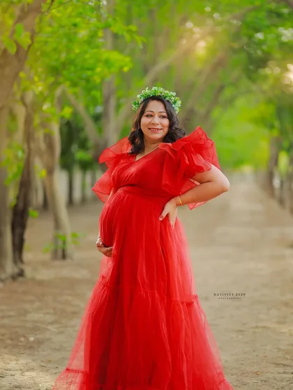 A radiant outdoor portrait in a red gown. The mother-to-be's happy expression and the beautiful natural light make this a joyful image.