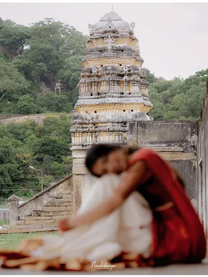 An artistic shot with the temple's gopuram in the background, while the couple is softly blurred in the foreground.