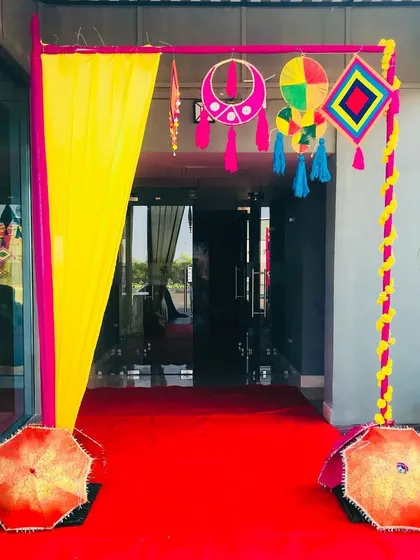 A colorful entrance for a Haldi ceremony, using vibrant drapes, Rajasthani-style hangings, and decorative umbrellas.