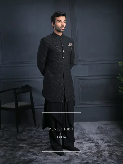 Not just attire, but an heirloom of style. This black self-textured achkan is adorned with regal silver buttons, flowing into draped kurta layers and wide trousers for unmatched elegance.