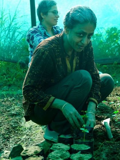 A workshop participant carefully transplants a delicate seedling into a poly bag, learning the skills needed to grow a forest.