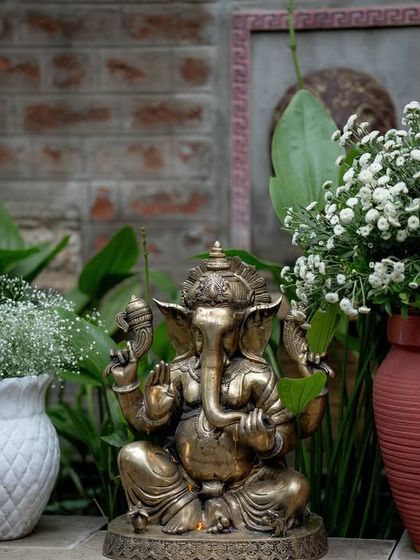 A brass Ganesha idol placed amidst floral decor, a traditional element to bring blessings to the celebration.