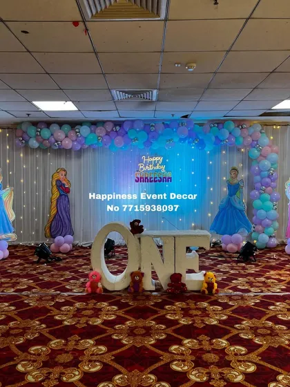 A centered shot of the princess first birthday stage, showing the full L-arch balloon arrangement over the twinkling fairy light curtain.