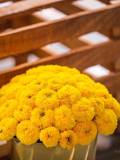 A detailed shot of a golden vase filled with marigolds, showcasing the textures and colors of the Haldi ceremony decor.