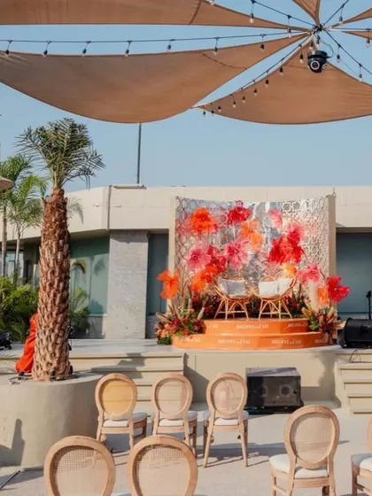 The main stage setup, with a backdrop of oversized, handmade paper flowers in shades of red and orange.