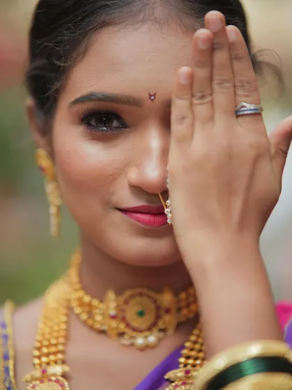 A close-up of a classic Maharashtrian look, focusing on the details. The expressive eyes, the traditional nath, and the perfectly matched gold jewelry come together to create timeless elegance.