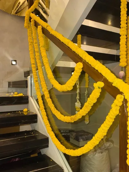 A modern staircase with its wooden railing wrapped in traditional marigold garlands for a festive Diwali touch.