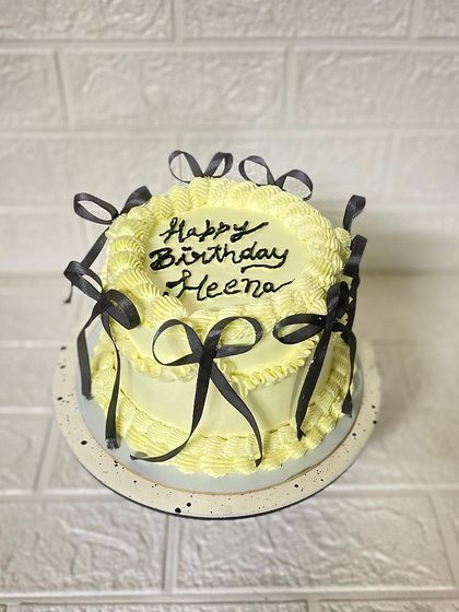 Going with the trend. A beautiful blackcurrant cake in a soft yellow, adorned with contrasting black ribbons.