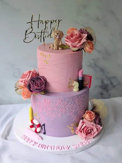 This cake was designed to capture everything the birthday girl loves. The two tiers in pink and lilac feature delicate stenciling, fresh flowers, and tiny, personalized fondant details like her pet dog, a lipstick, and a musical note, making it a truly unique and personal gift.
