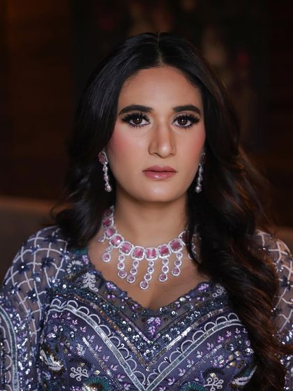 A close-up of this dreamy cocktail glam. The focus is on the bold, smoky eye and the flawless, glowing skin, paired with a statement pink diamond necklace.