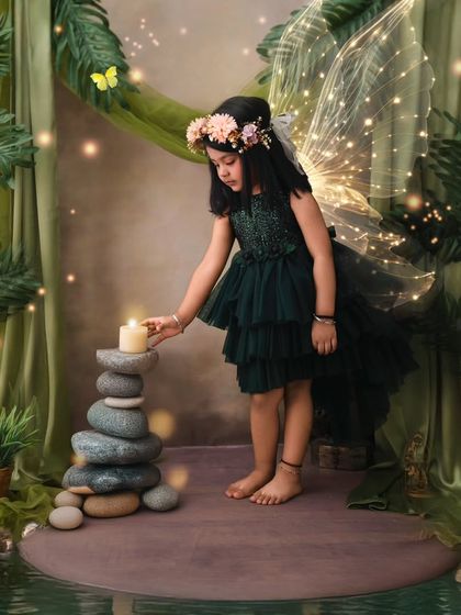 In an enchanted forest by the water, this little fairy gently touches a candle, her wings glowing softly.