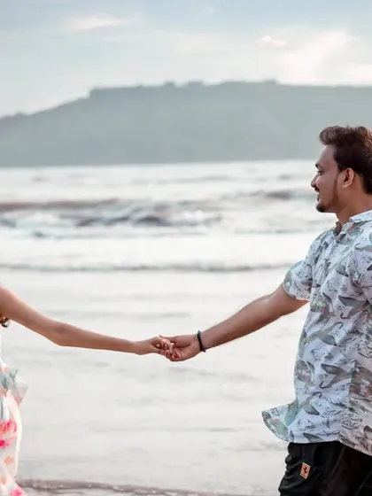 The simple act of holding hands while walking along the shoreline. This candid pre-wedding photo focuses on the connection between the couple, with the beautiful Alibag coastline in the background.
