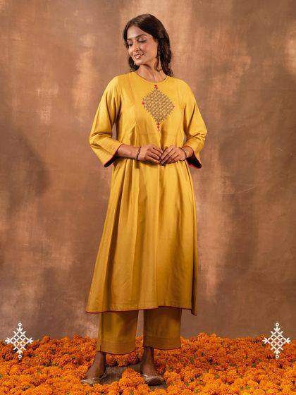 The Ruhani Yellow Pleated Kurta, standing on a bed of marigolds, evokes the vibrant spirit of Indian festivities. Its flowing silhouette and rich color make it a joyful addition to any wardrobe.