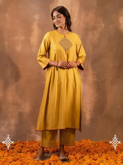 The Ruhani Yellow Pleated Kurta, standing on a bed of marigolds, evokes the vibrant spirit of Indian festivities. Its flowing silhouette and rich color make it a joyful addition to any wardrobe.