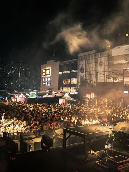 Black Coffee at the decks, with the massive outdoor venue and crowd stretching out behind him.