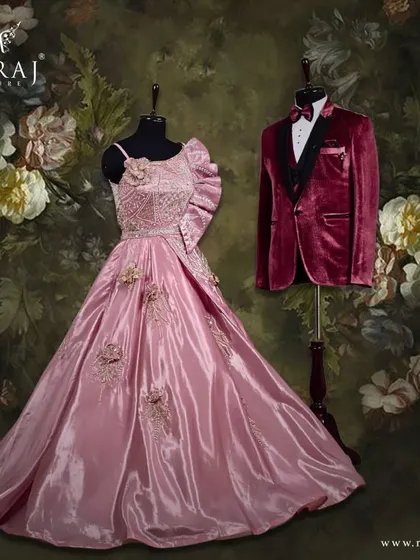 For the picture-perfect reception. This coordinated set features a stunning off-shoulder peach gown with floral appliqué for her, and a classic red velvet suit for him, creating a fashion pairing that captures hearts.