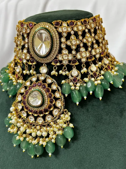 A close-up view of one of my most detailed bridal chokers for rent. This piece features intricate Kundan work, green beading, and a large central pendant, perfect for making a statement.