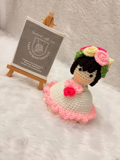 A close-up of another reversible doll, this one with a lovely pink-trimmed dress and a sweet floral detail at her collar. Every doll is handmade with soft cotton yarn.