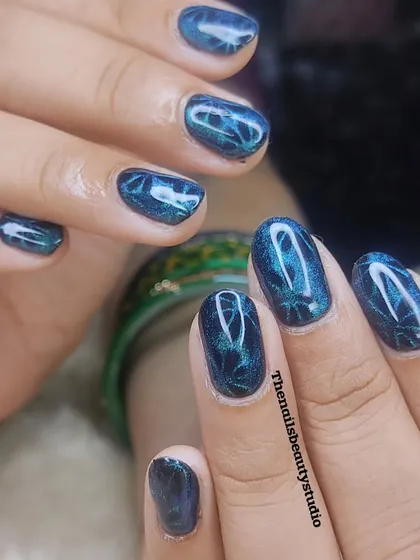 A close-up of this gorgeous blue-green cat-eye manicure on short, rounded nails.