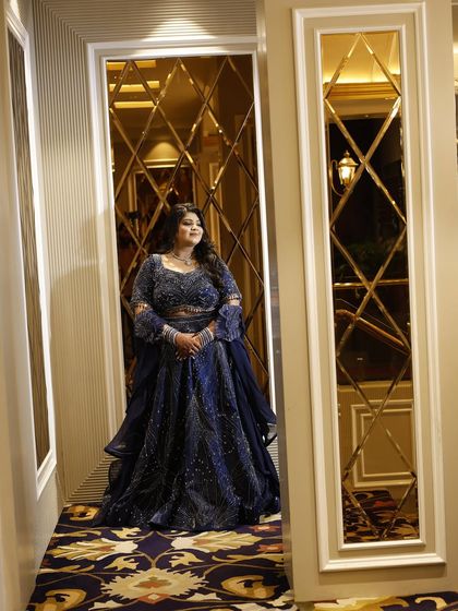 The same client in her custom-fit navy blue lehenga, framed by beautiful mirrored walls. The outfit sparkles and shines from every angle.