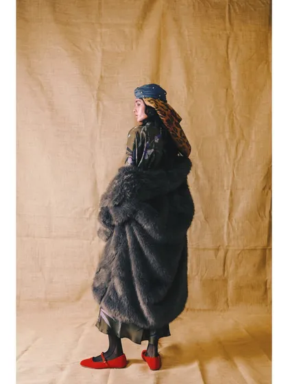 A more subdued look from 'Neo-Boheme', featuring a voluminous fur-textured coat and layered headscarves. The pop of red from the shoes adds a surprising, stylish detail.