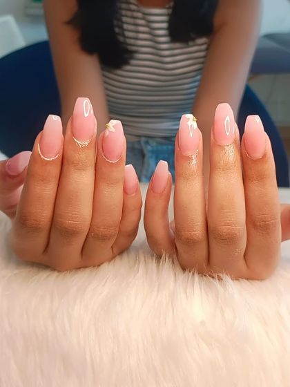 Delicate floral nails featuring a sheer pink base with tiny, hand-painted white flowers and gold accents.