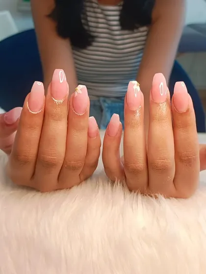 Delicate floral nails featuring a sheer pink base with tiny, hand-painted white flowers and gold accents.