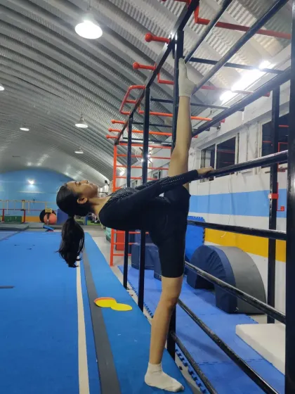Using the wall bars for support, this student achieves a full vertical split. This type of stretching is key to developing the flexibility required for elite gymnastics.