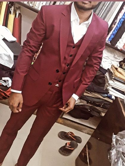 This client is trying on his new maroon three piece suit in my shop. This color is very popular for weddings and festive occasions, and I ensure the fit is perfect before the final delivery.