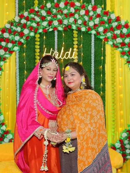 A sweet moment between friends at a Haldi ceremony. My client is wearing a yellow floral set, while her friend wears a pink and orange one, also made by me.