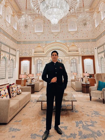 Standing in a lavishly decorated hotel lounge. The opulent surroundings call for a sharp and significant look.