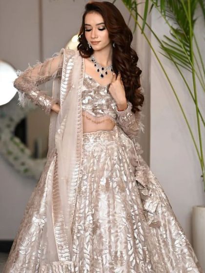 Two shots of a stunning silver and beige lehenga with feather-detailed sleeves. This is a sophisticated and modern choice for an engagement or reception look.