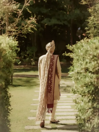 A thoughtful back shot of the groom, William, as he walks through a garden path. This creates a sense of anticipation and highlights the beautiful details of his attire.